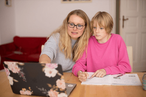 A mother and young child reviewing homework together at home.
