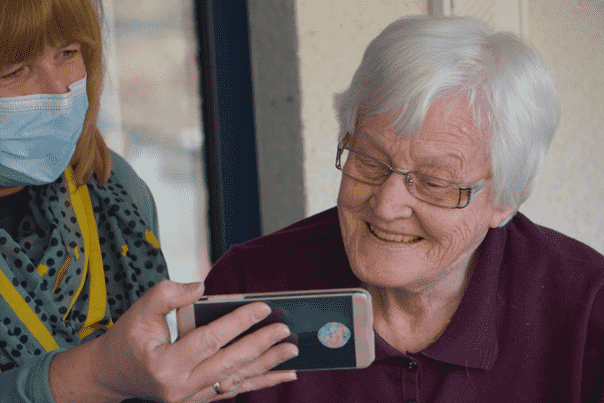 a person showing an elderly woman something on their phone