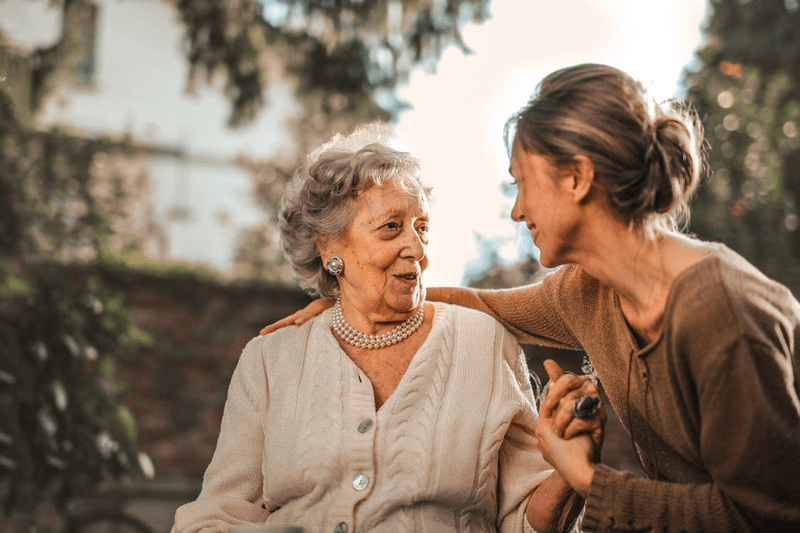  a girl talking to an elderly woman compassionately