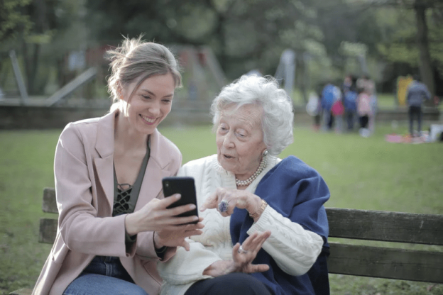 a person showing an elderly woman something on their phone