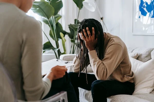 Support worker listening to a man with his head in his hands.