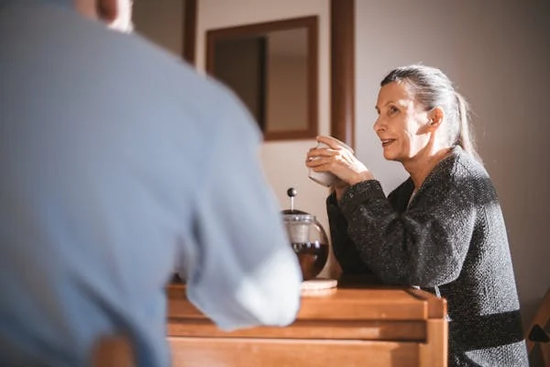 A woman enjoying tea in a retirement home with support from care staff.