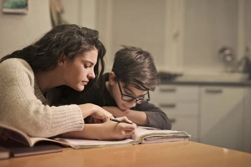 A long-term support worker teaching a young boy in a children’s home, fostering education and trust.