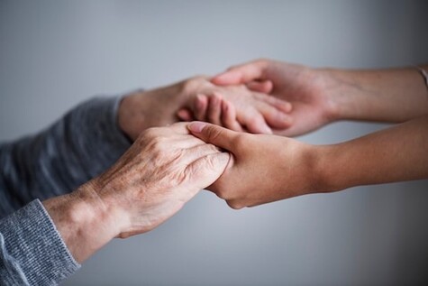 A closeup of a support worker holding hands with a homeless person 