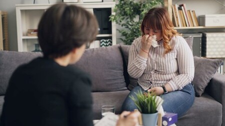 A female support worker talking to a female resident who is crying while using a tissue