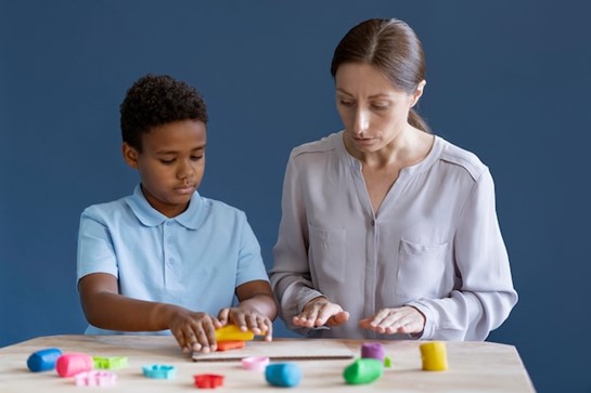 A female support worker teaching a boy