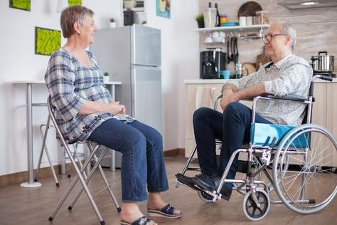 Elderly woman talking to her disabled husband.