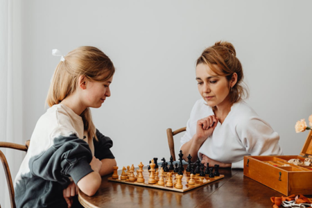 A teen playing chess with an adult