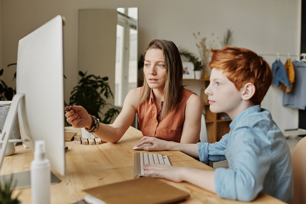 A person and a teen looking at a computer