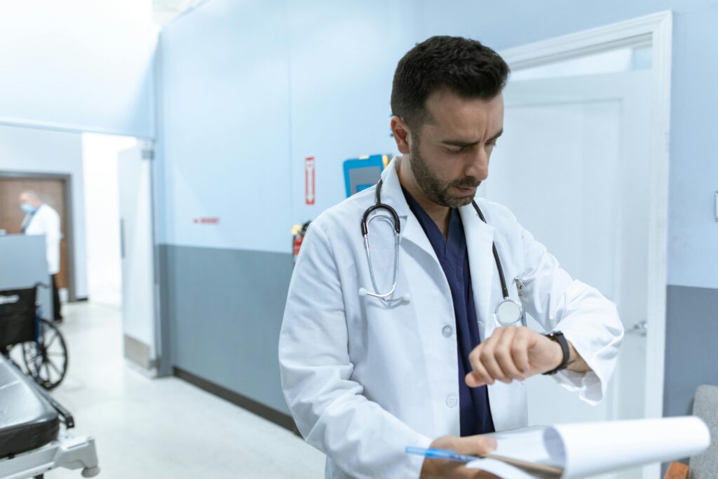 Physician in a busy clinic checking his watch while managing patient schedules