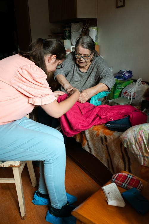 Support worker assisting a senior resident with a sewing activity in a care setting