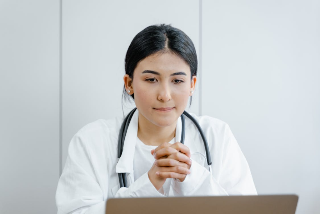 A person in white scrubs watching a screen