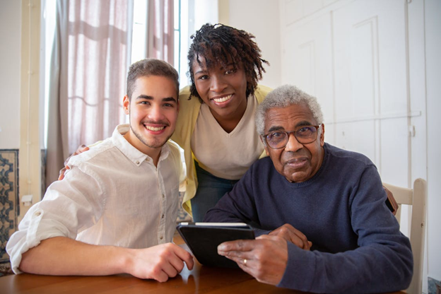 A photo showing two support workers with a senior individual at a table.