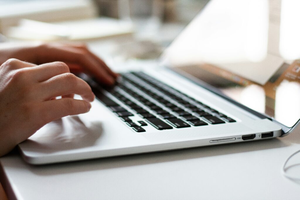 close-up of hands typing on a laptop during care documentation