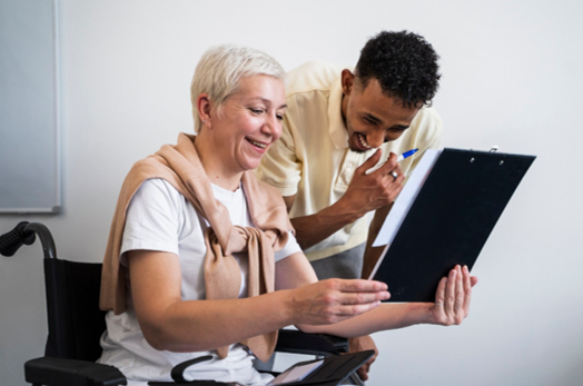 Support worker guiding woman in wheelchair through residential care setting