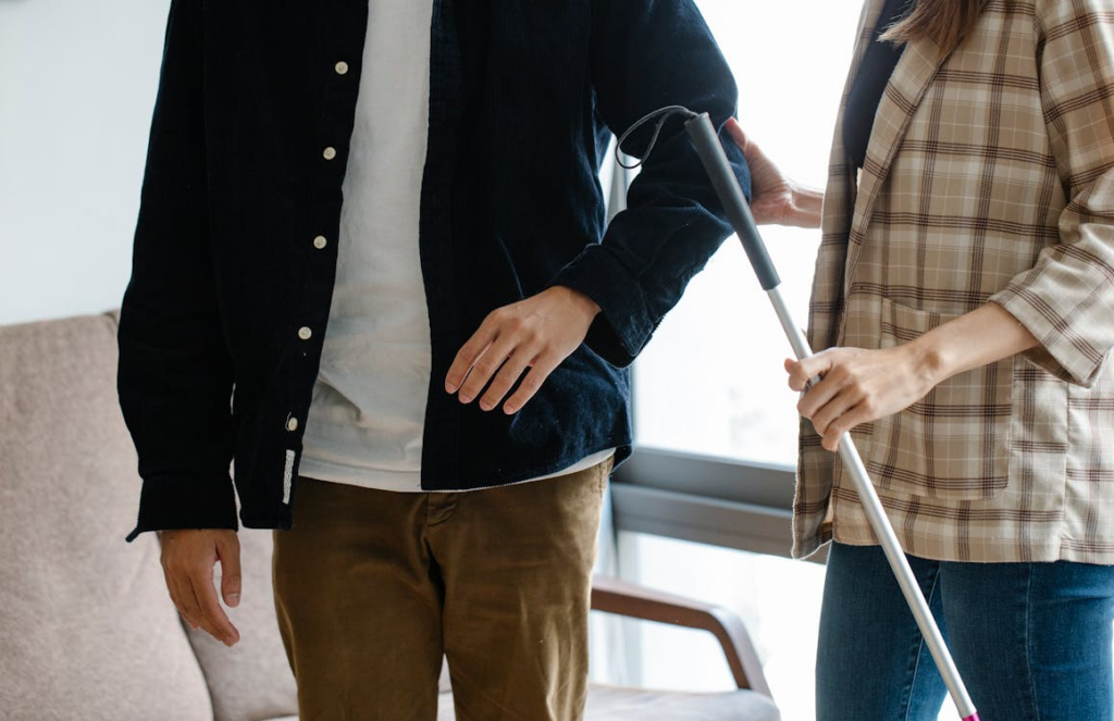 A person helping another with a walking stick 