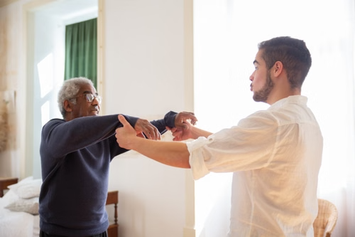 A male support worker with a male senior resident helping him with exercise