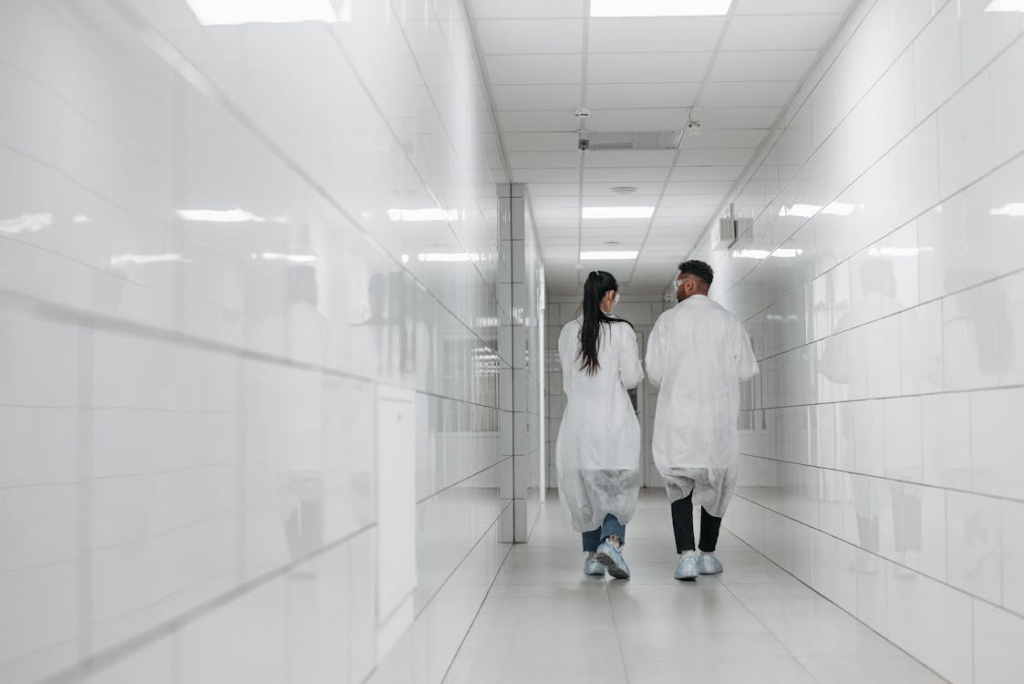 An image of two people wearing white coats while walking down the hallway   
