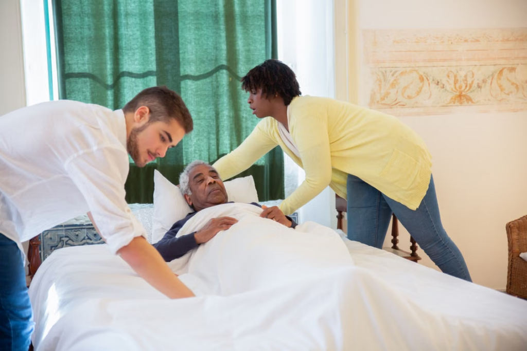 Support workers tucking an elderly in a bed 