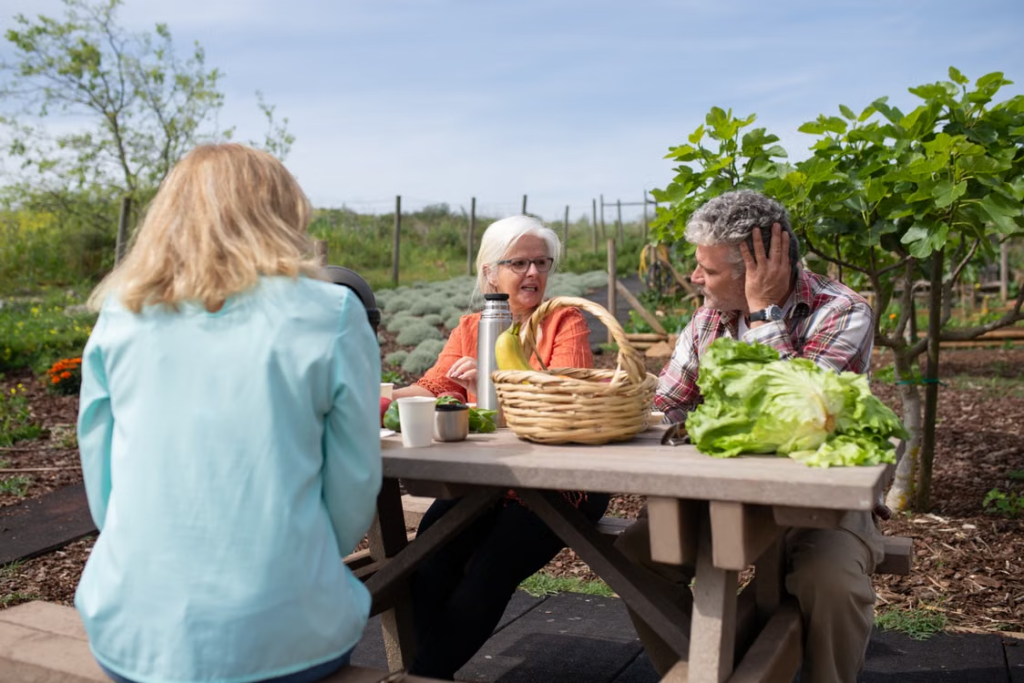 Senior residents enjoying conversation in a retirement village community garden after gardening activities.