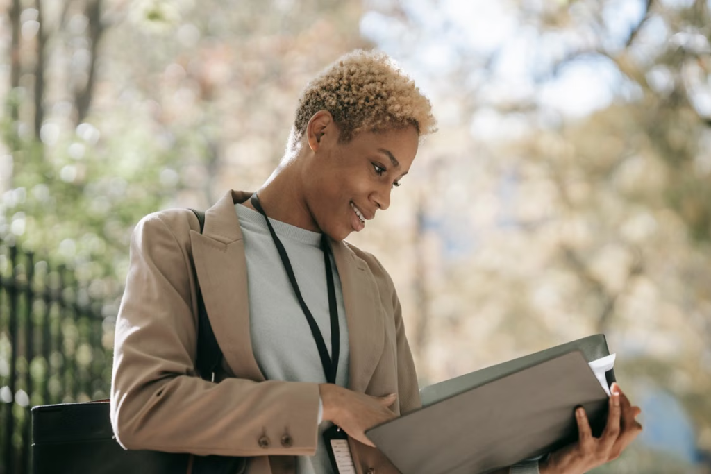 A support worker wearing an ID lanyard reviewing case files outdoors.