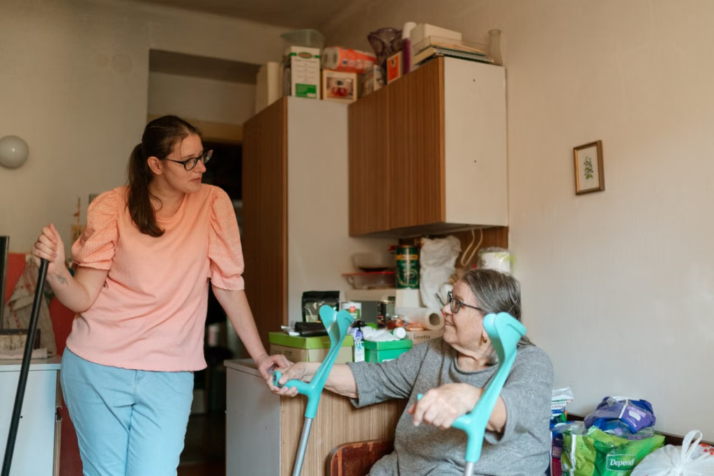 A support worker holding hands with a resident using mobility aids.