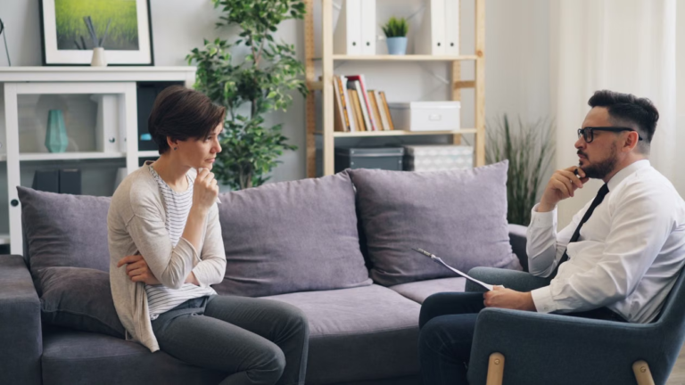 A support worker having a serious, focused conversation with a young person while taking notes.