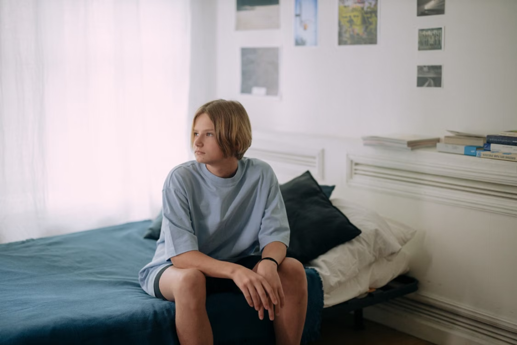 a young boy sitting on a bed.